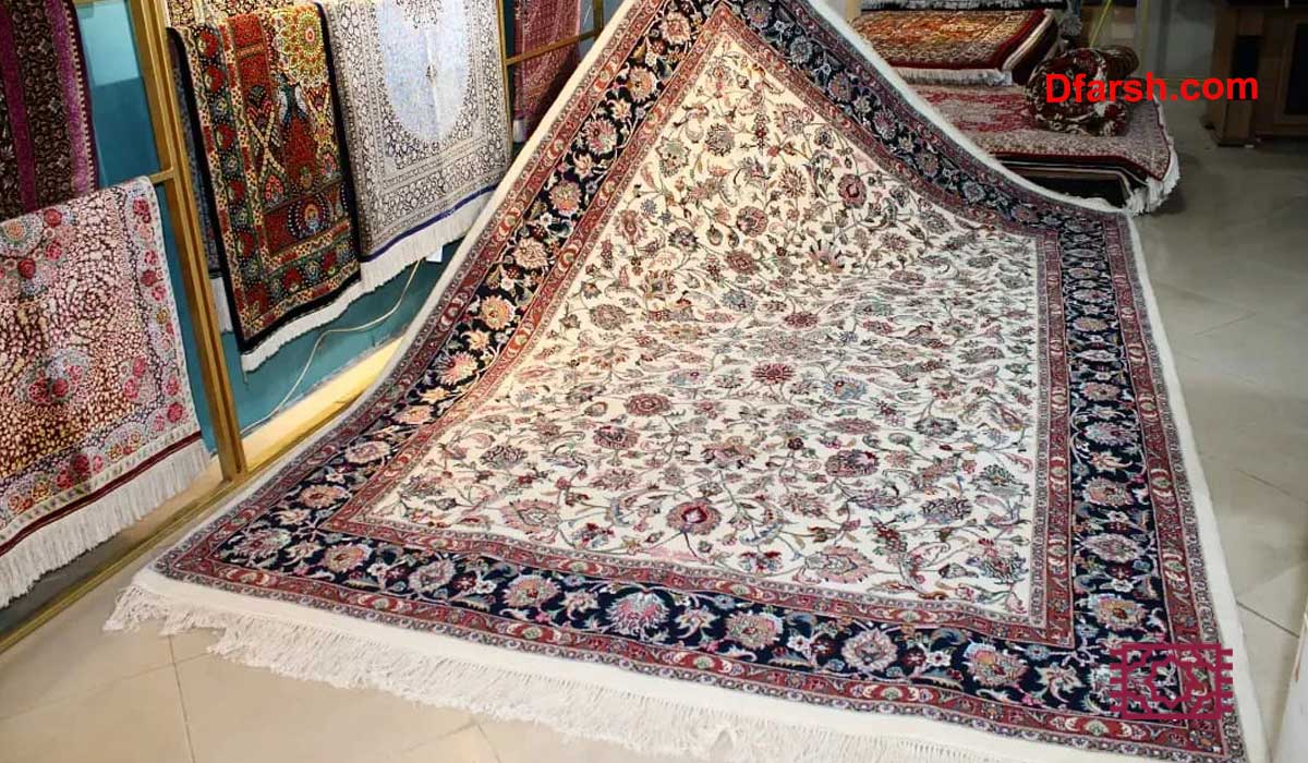 فرش مشهد اصیل با زمینه کرم، حاشیه سرمه&zwnj;ای و نقوش کلاسیک گل&zwnj;دار